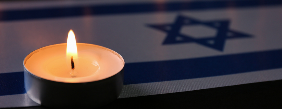 A lit candle sits on an Israeli flag, possibly signifying remembrance or memorial of October 7.