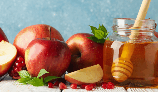 Apples, pomegranate seeds, and a jar of honey with a dipper, symbolizing sweetness and festivity. 18doors.